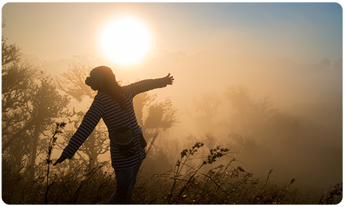 An image of an individual with their arms spread out in a misty field